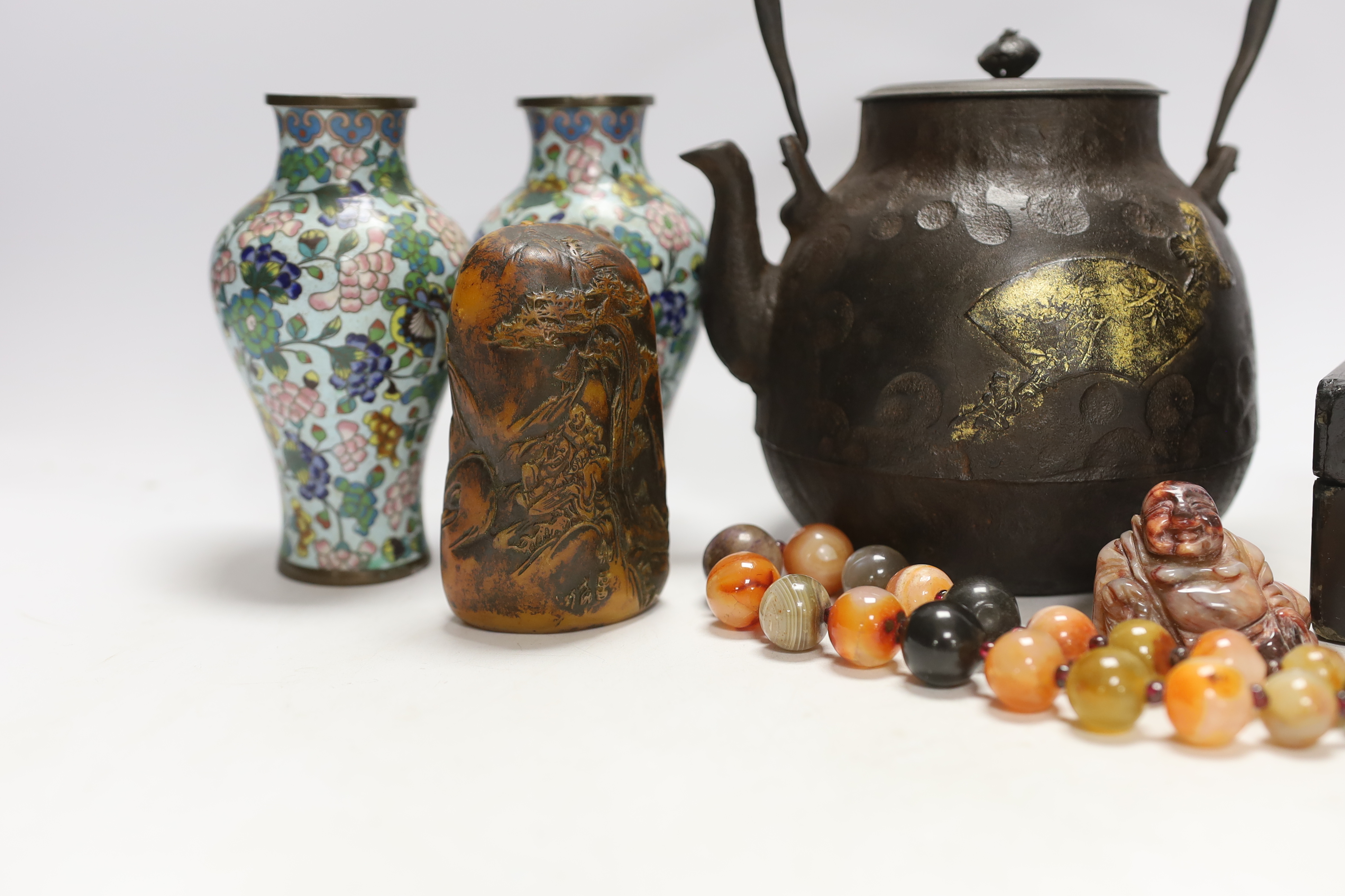 A Japanese iron tetsubin kettle with gilt decoration, a pair of Chinese cloisonné enamel vases, 12.5cm, a lacquered box with mother of pearl inlay, a carved black stone disc, 5cm diameter, a miniature ceramic pot and an